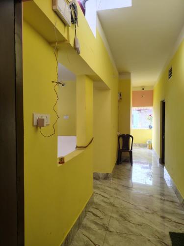 an empty hallway with yellow walls and a chair at Shivmandir Homestay in Siliguri