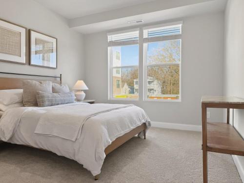 a white bedroom with a bed and a window at Luxe King Bed, Balcony, Garage in Downtown Raleigh in Raleigh