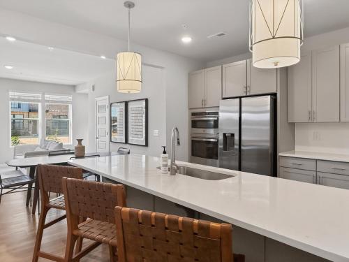 a kitchen with a large white counter and chairs at Luxe King Bed, Balcony, Garage in Downtown Raleigh in Raleigh