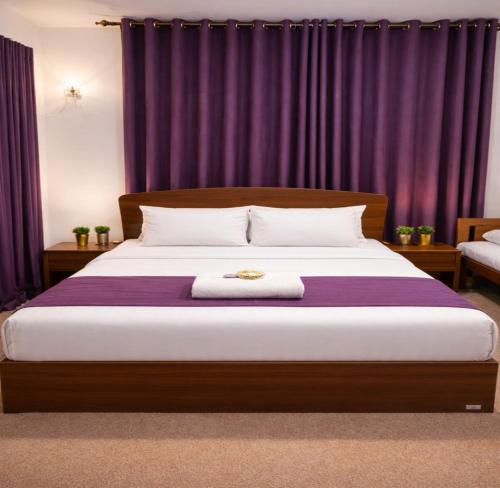 a bedroom with a large bed with purple curtains at Premier Stay in Chavakachcheri