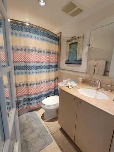 a bathroom with a toilet and a sink and a shower at 108 Sapphire Beach Condos Barbados in Christ Church