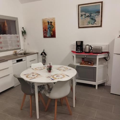 La Maisonnette في Issenheim: مطبخ به طاولة وكراسي بيضاء في غرفة