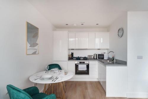 a kitchen with white cabinets and a table and chairs at Stay Zeni, Alexandra Rise Manchester Sleek Studio in Manchester