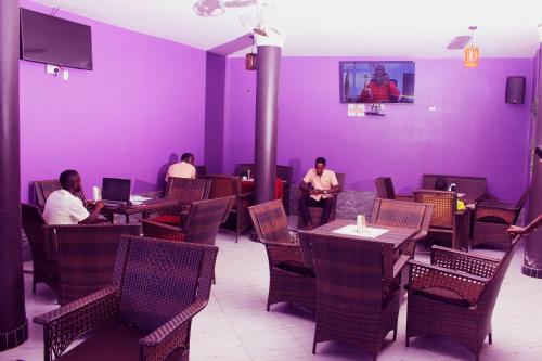 a group of people sitting in a restaurant with purple walls at Moto-Moto Cottages in Mbarara