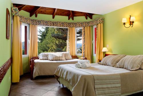 a bedroom with two beds and a large window at Solar de las Araucarias in San Carlos de Bariloche