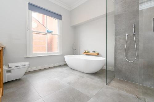 a white bathroom with a tub and a shower at Stylish Leeds City Centre Retreat with Private Terrace & Hottub in Central Station