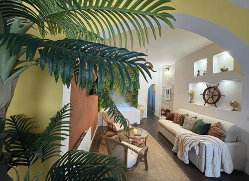 a living room with a couch and a palm tree at La suite Carthagène des Indes - centre ville , spa & terrasse privée in Béthune