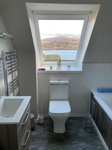 a bathroom with a white toilet and a window at Skyefall Apartment in Uig