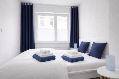 a white bed with blue pillows and a window at Haus Wilbrand Ferienzimmer 1 in Warnemünde