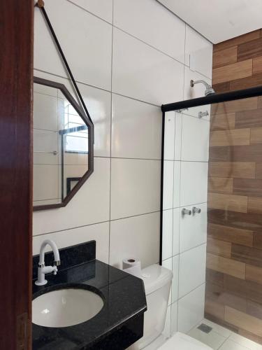 a bathroom with a sink and a toilet and a mirror at Pousada Avenida Farol in Campos dos Goytacazes