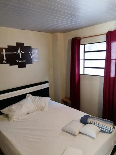 a bedroom with a white bed with red curtains and a window at Cozy apartment close to everything in Asunción