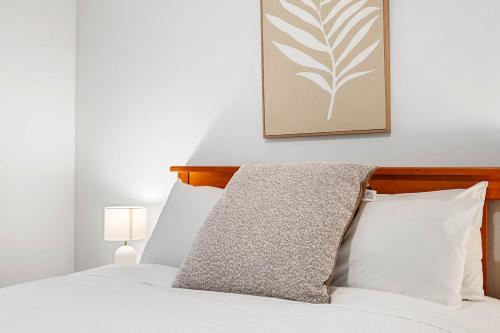 a bed with white pillows and a picture on the wall at Sunny Side Studio - Mosman Park in Mosman Park