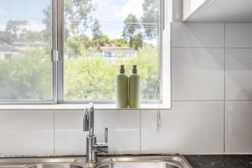 two bottles sitting on a window sill above a kitchen sink at Sunny Side Studio - Mosman Park in Mosman Park
