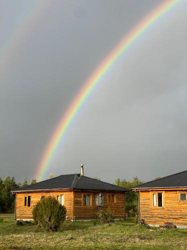 a rainbow in the sky over a wooden house at Cabañas Kuela in Puerto Varas