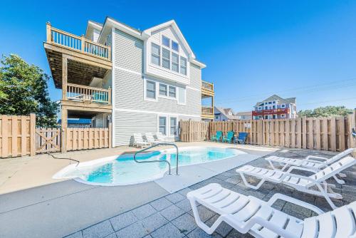 a swimming pool with lounge chairs and a house at On Island Time - KDH MP 7, 275 Yds to Beach, Pool, Hot Tub, Pool Table, Flex Stays in Kill Devil Hills