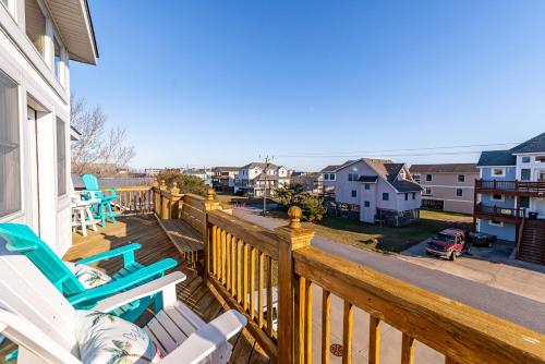 a balcony with rocking chairs and a view of a street at On Island Time - KDH MP 7, 275 Yds to Beach, Pool, Hot Tub, Pool Table, Flex Stays in Kill Devil Hills