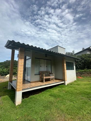 a small house with a deck with a bench on it at Chalé Face de Cristo in Caparaó Velho