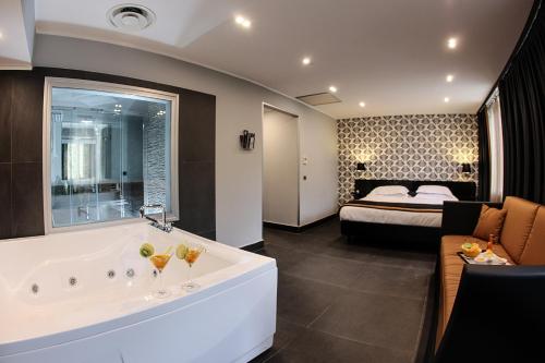 a large bathroom with a tub and a bedroom at Best Western JFK Hotel in Naples