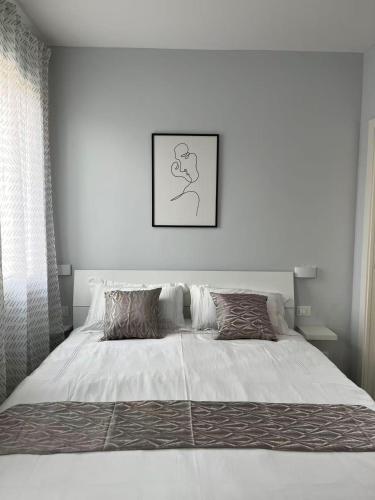a white bedroom with a large bed with two pillows at James Home in Quarto dʼAltino