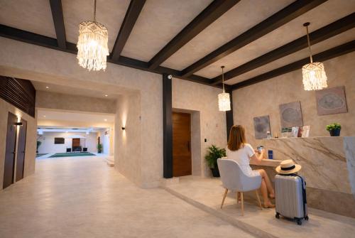 a woman sitting at a table with a suitcase in a lobby at Hotel Pakal 58 Centro in Mérida