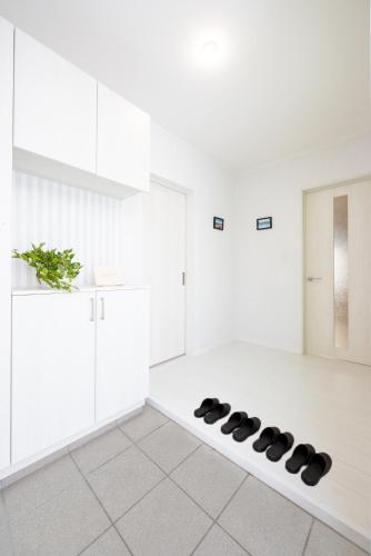 a kitchen with white cabinets and black shoes on the floor at BIEI BREEZE RESERVE Sui 水 in Biei