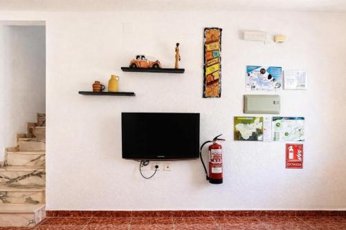 a flat screen tv on a white wall with shelves at Manomar II, tu refugio en Gata in Gata