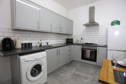 a kitchen with white cabinets and a washer at Contractor House, 4 Bed Ensuite, Near Stadium in Wolverhampton
