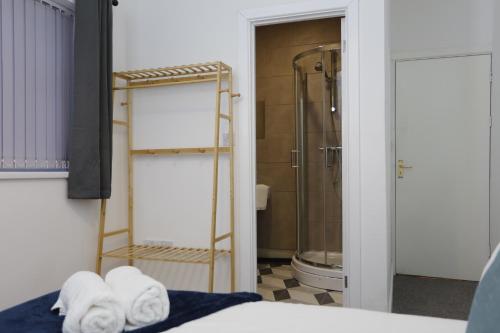 a bathroom with a shower and towels on a bed at Contractor House, 4 Bed Ensuite, Near Stadium in Wolverhampton