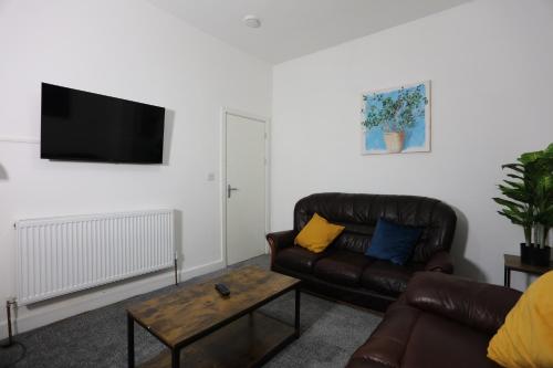 a living room with a leather couch and a coffee table at Contractor House, 4 Bed Ensuite, Near Stadium in Wolverhampton