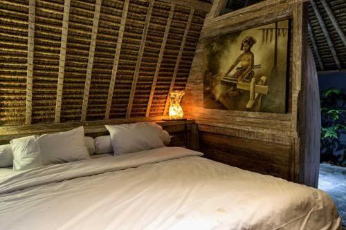 a bedroom with a white bed with a picture on the wall at Gipsy Beach Bungalows in Sekotong