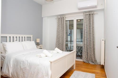 a white bedroom with a white bed and a window at E25 by SpitiSou in Athens