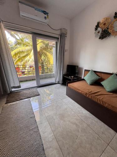 a living room with a bed and a large window at Estudio 007, Palolem in Canacona