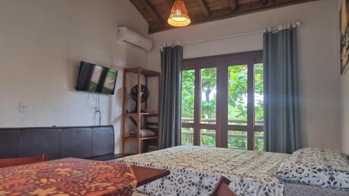 a bedroom with a bed and a sliding glass door at Recanto das Amendoeiras in Guarda do Embaú
