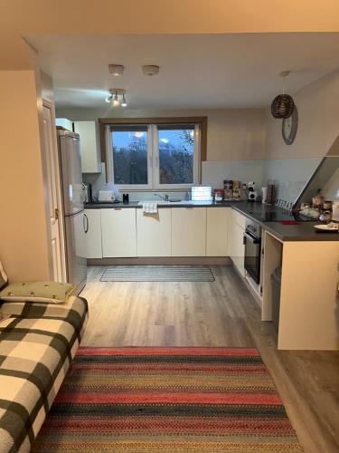 a kitchen with white cabinets and a large window at “A Wee Pad in Dunfermline” in Dunfermline