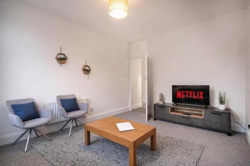 a living room with a tv and two chairs and a table at 3-Bedroom Flat-FreeParking & Wifi, Sleeps7 in Bristol