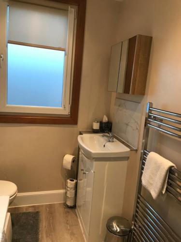 a bathroom with a sink and a toilet and a window at “A Wee Pad in Dunfermline” in Dunfermline