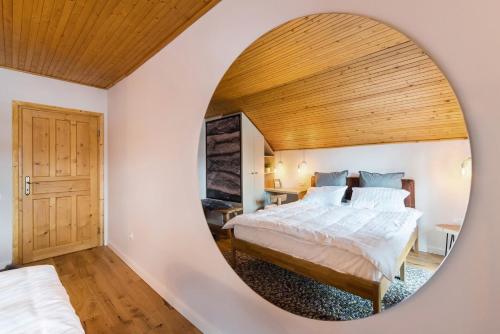 a bedroom with a bed and a round mirror at Heritage Villa Predelut - Fireplace & Baby Crib in Predeluţ