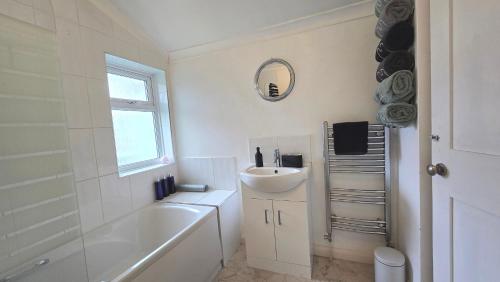 a white bathroom with a sink and a tub and a mirror at Mayfield , 2 bed slp 6 Roomy dog friendly Gosport town house in Gosport