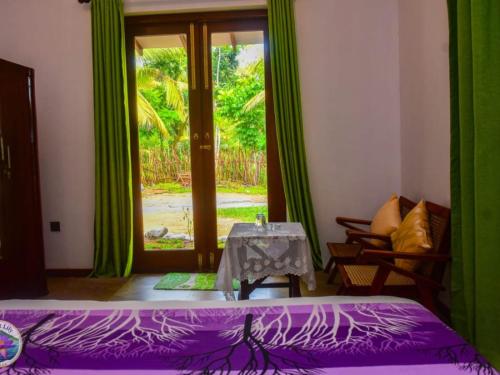 a bedroom with a purple bed and a table and a window at Mount Lily Mirissa in Mirissa