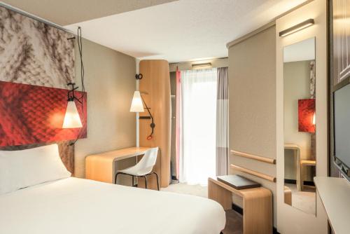 
a hotel room with a bed, chair, and nightstand at Ibis Paris Gare Montparnasse 15ème in Paris
