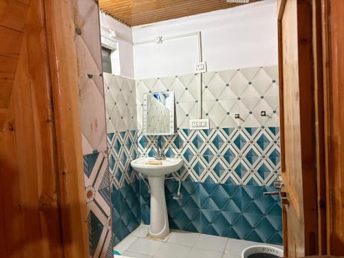 a bathroom with a sink and blue and white tiles at The Tree Hub Jibhi in Jibhi