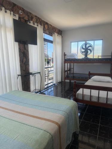 a hotel room with two beds and a television at Pousada Ju Haus in Navegantes