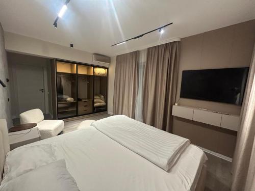 a bedroom with a bed and a flat screen tv at Studio in Dimri Residence in Bucharest