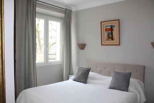 a bedroom with a white bed and a window at Hotellerie de l'Esplanade in Rians