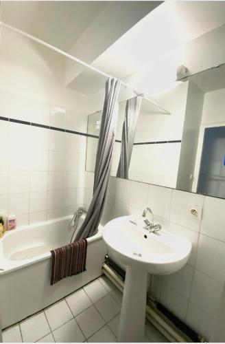 a white bathroom with a sink and a bath tub at Paris Saint Maurice Montgolfier in Saint-Maurice