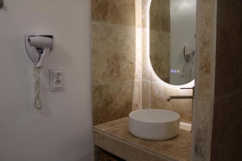 a bathroom with a sink and a phone on a counter at Hotellerie de l'Esplanade in Rians