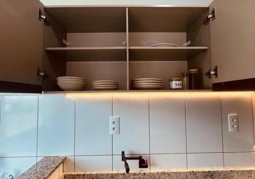 a kitchen with white cabinets and plates on shelves at Apartamento com ar condicionado e lava e seca in Cascavel