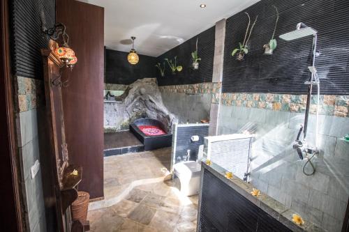 a bathroom with a shower and a toilet and a fireplace at Avalon Ubud Castle & SPA in Ubud