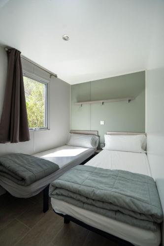 two beds in a room with a window at Camping Ridaura in Llagostera