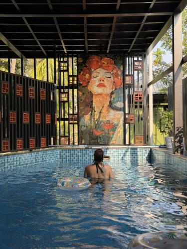 a woman in a swimming pool with a painting at Oblue Private Pool Villa in Cherai Beach